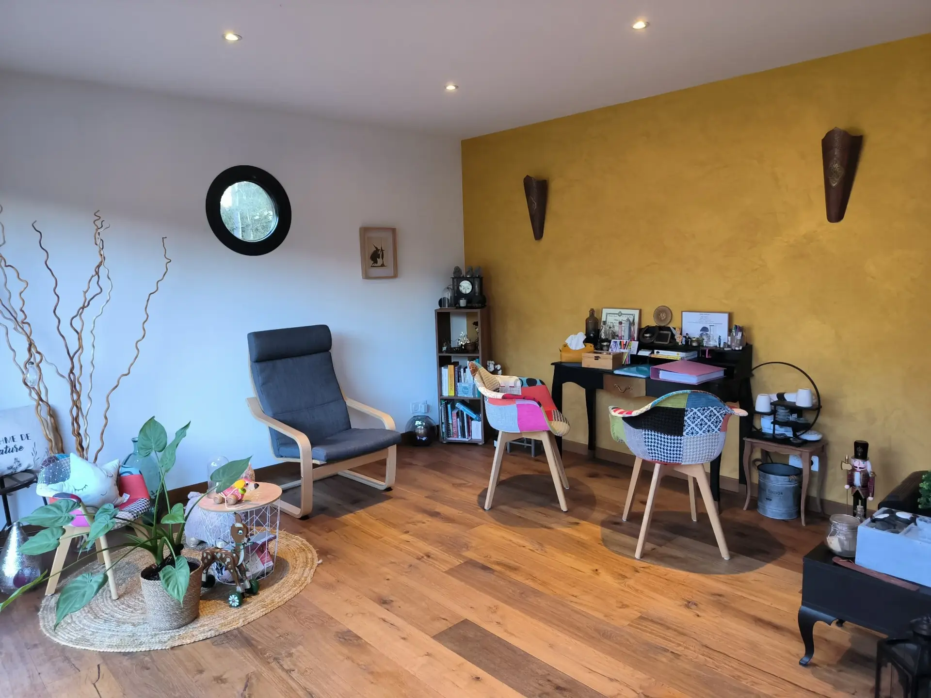 L'intérieur du cabinet : mur ocre, fauteuil et hublot de bois